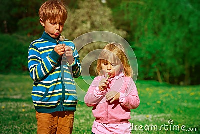 Little boy and girl blow dandelions, play in spring nature Stock Photo