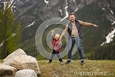 Cute little boy and his father walks in Swiss national Park on spring. Hiking with little kids. Dangerous situation: standing on Stock Photo