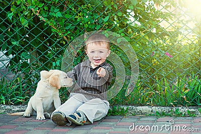 Cute little boy kneeling with his puppy labrador smiling at camera Stock Photo