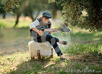 Cute little boy is playing guitar in the park Stock Photo