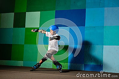 Cute little boy on roller skates running against the blue graffiti wall Stock Photo