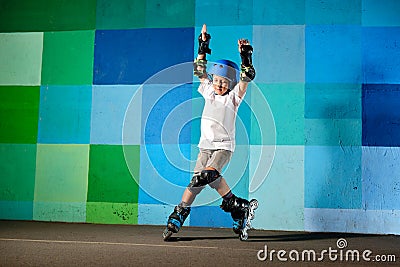 Cute little boy on roller skates running against the blue graffiti wall Editorial Stock Photo