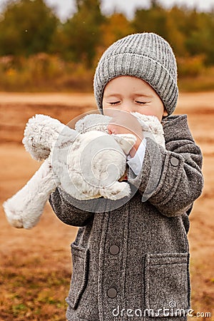 Little boy tenderly kisses his toy bunny with his eyes closed Stock Photo