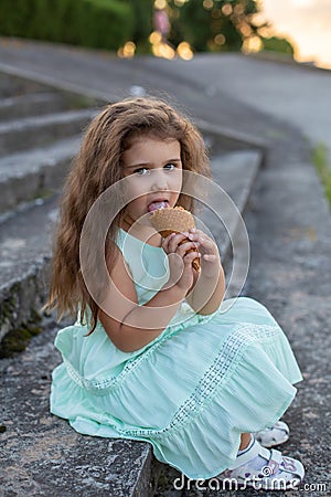 Vertical closeup portrait of a pretty little girl on the background of the steps of a summer park Stock Photo
