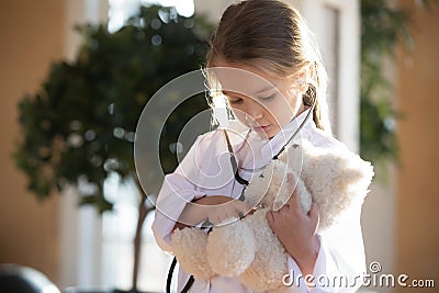 Little girl child act as doctor cure teddy bear Stock Photo