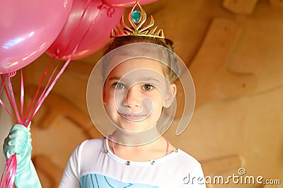 Cute little caucasian seven year old children girl at home in a costume elsa frozen with a golden crown and pink balloons cheerfu Stock Photo