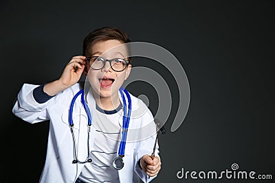Cute little child in doctor uniform with reflex hammer on black background. Stock Photo