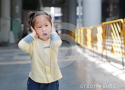 Cute little child girl shutting down her ears, holding her hands covers ears not to hear Stock Photo