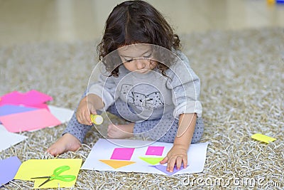 Cute little child make applique, glues colorful house. Stock Photo