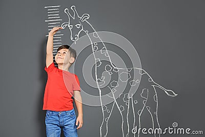 Cute little child measuring height near chalk giraffe drawing Stock Photo