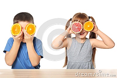 Cute little children with citrus fruits at table on white background Stock Photo