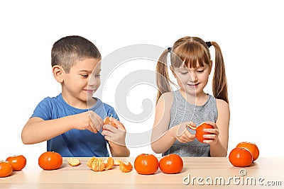 Cute little children eating citrus fruit at table on white background Stock Photo
