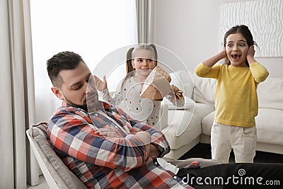 Cute little children popping paper near father while he sleeping at home Stock Photo