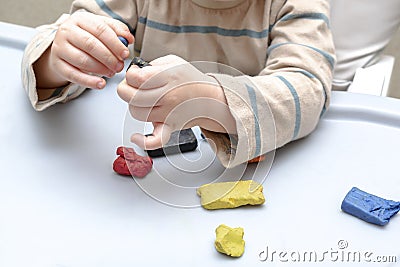 Cute little childrens hands playing at home, molding multi-colored plasticine, sculpts with colored clay stucco. Playdough, clay Stock Photo