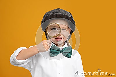 Cute little detective with magnifying glass on yellow background Stock Photo