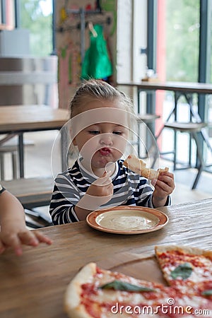 Cute little 2 years girl eating pizza in the restaurant Stock Photo