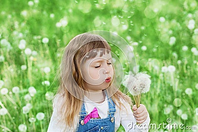 Cute little girl blowing dandelion on the flower meadow, happy childhood concept Stock Photo