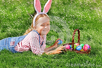 Cute little girl child with basket on green grass in the park. Easter Egg Hunting Concept Stock Photo