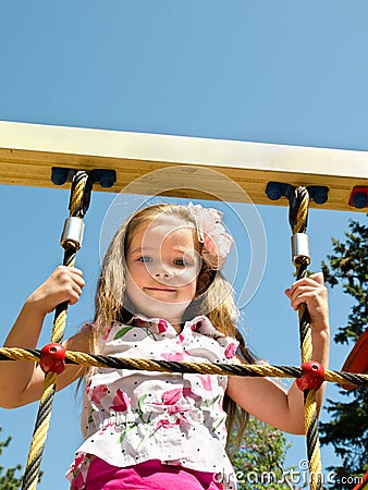 Cute little girl is climbing up on ladder in playground Stock Photo