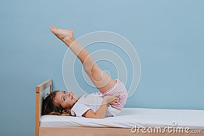 Cute little girl doing morning gymnastics in bed. Candlestick exercise Stock Photo