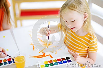 Cute little girl drawing with colorful paints at a daycare. Creative kid painting at school. Stock Photo