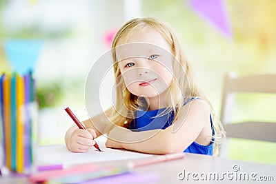 Cute little girl drawing with colorful pencils at a daycare. Creative kid painting at school Stock Photo