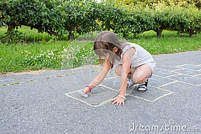 A cute little girl draws with chalk on the pavement in the park Stock Photo