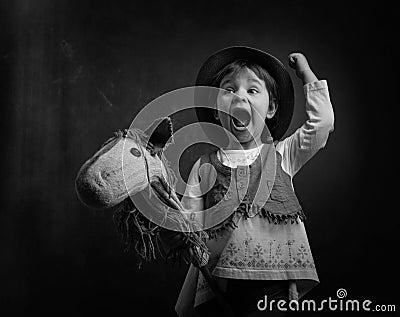 Cute little girl dressed like a cowboy playing with a homemade h Stock Photo