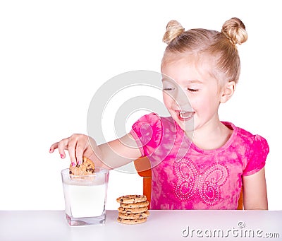 Cute little girl dunking cookie in milk Stock Photo