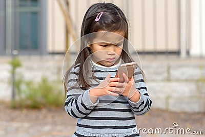 Cute little girl fascinated by a mobile phone Stock Photo