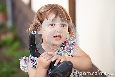 Cute little girl with father`s drill, outdoors. Stock Photo