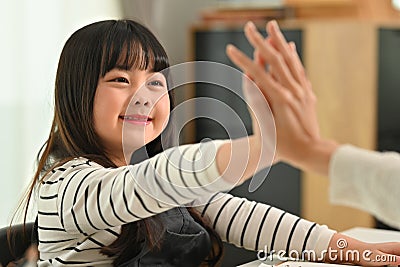 Cute little girl finish schoolwork giving high five to mother. Distance education, homeschooling concept Stock Photo