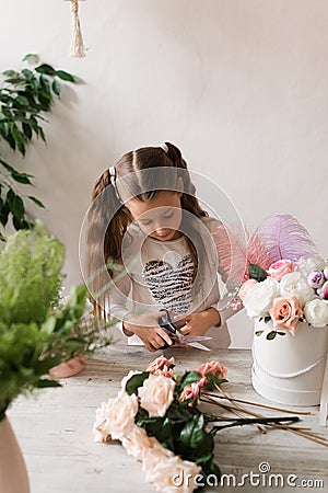 little girl florist collects a bouquet of flowers at the table Stock Photo