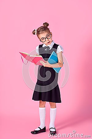 Cute little girl with glasses and books on pink background, space for text. Reading concept Stock Photo