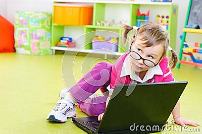 Cute little girl in glasses with laptop on floor Stock Photo