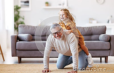 Cute little girl granddaughter playing and having fun with active positive grandfather at home Stock Photo