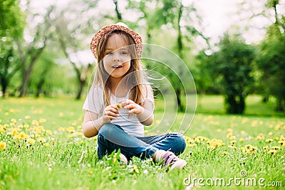 Cute little girl with hat siting on the grass. Stock Photo