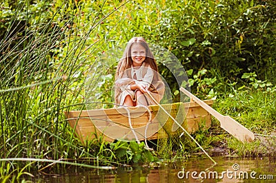Cute little girl having fun in a boat by a river Stock Photo