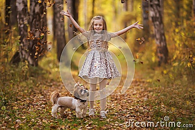Cute little girl with her dog in autumn park. Lovely child with dog walking in fallen leaves. Stock Photo