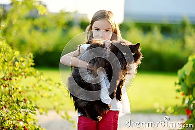 Cute little girl holding giant black cat Stock Photo