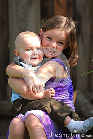 Cute little girl holds a baby boy and smiles Stock Photo