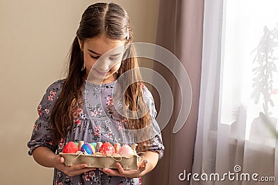 A cute little girl holds a cardboard tray with colorful eggs Stock Photo