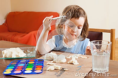 Cute little girl learning to paint dough figurines Stock Photo