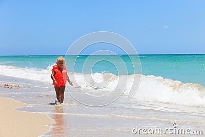 Cute little girl in life jacket on summer beach, safety Stock Photo