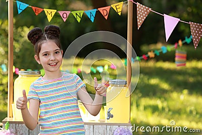 Cute little girl near lemonade stand in park. Summer refreshing natural drink Stock Photo