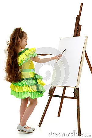 Little girl with a palette and brush near the easel. Stock Photo