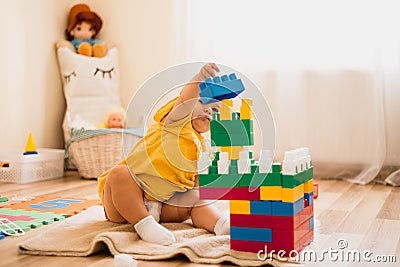 Little girl playing with construction toy blocks building a tower in a sunny kindergarten room Stock Photo