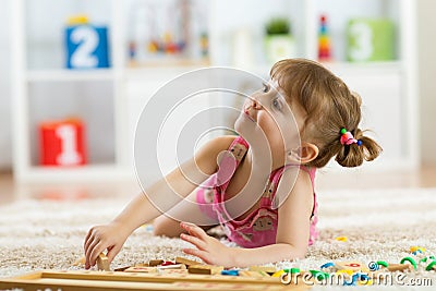 Cute little girl playing with educational toy blocks in a sunny kindergarten room. Kids playing. Children at day care. Stock Photo