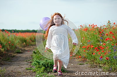 Cute little girl playing in a field with balloon. Summer poppy f Stock Photo