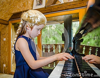 Cute little girl playing piano, dressing in retro Mozart periwig Stock Photo